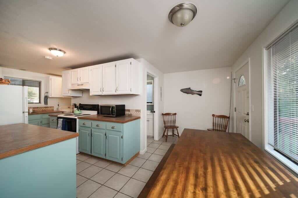 Een keuken met witte kasten, een houten aanrecht en een eethoek met een houten tafel.