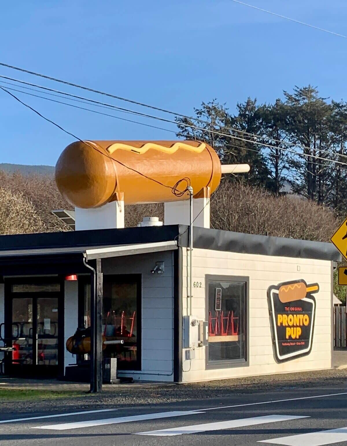 A building with a large hot dog sign on the side, a small entrance, and a number 602 on the door.