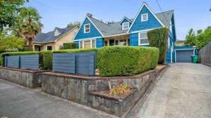 A row of two-story houses with blue and beige exteriors, stone retaining walls, and well-maintained hedges.