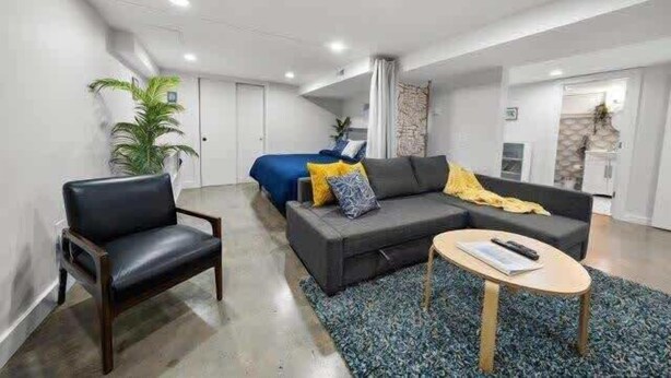 A modern living room with a sofa, a chair, a coffee table, and a patterned rug.