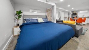 A modern bedroom with a large bed, a desk, and a chair.