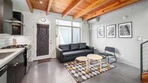 Eine moderne Küche mit Herd, Backofen und einer schwarzen Couch in einem Wohnbereich mit Couchtisch und einem gemusterten Teppich.