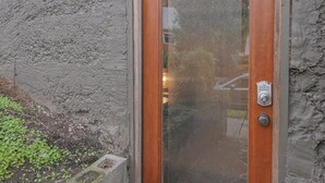 Puerta de madera con un panel de vidrio y un timbre de metal.