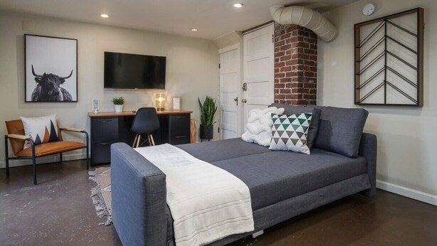 Un dormitorio con cama, escritorio, silla, televisión y chimenea de ladrillo.