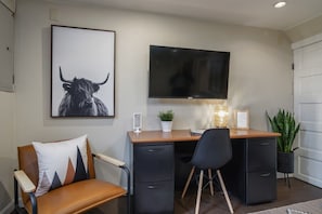 A modern office space with a desk, chair, television, and decorative items.