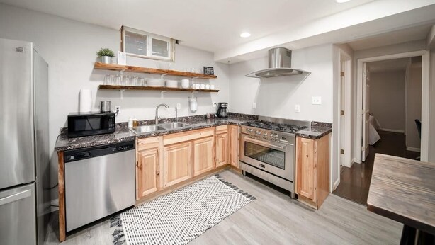A modern kitchen with stainless steel appliances, wooden cabinets, and a granite countertop.