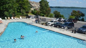 Une piscine avec des chaises longues et un parking.