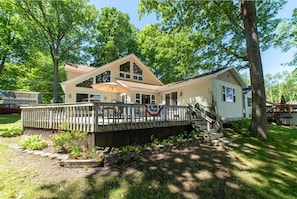 A two-story house with a deck, a staircase, and a flag.