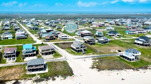 Vue aérienne d’une zone résidentielle côtière, avec des maisons, des routes et une plage.
