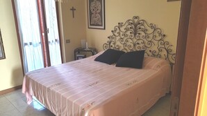 Quarto com uma cama, uma cruz na parede e um quadro emoldurado.