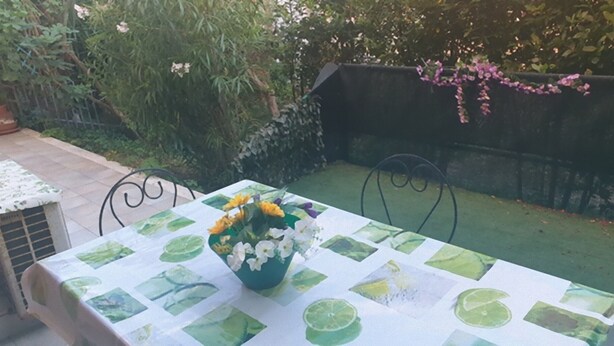 Uma mesa com toalha decorada com motivos de folhas de limão, rodeada por cadeiras.