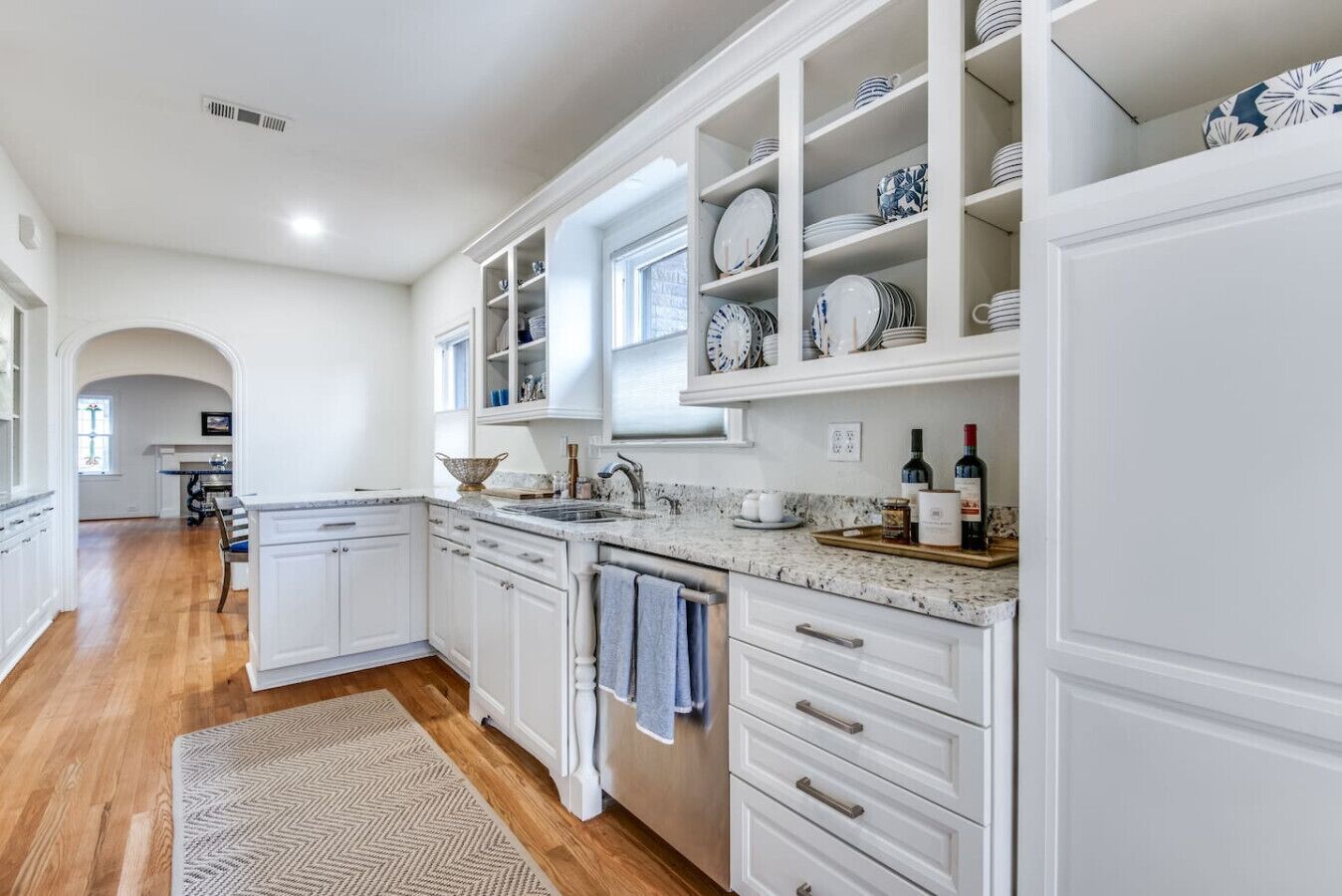 A modern kitchen with white cabinetry, a granite countertop, and a built-in wine rack.