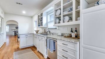 A modern kitchen with white cabinetry, a granite countertop, and a built-in wine rack.