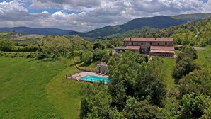 Ein ländliches Anwesen mit Schwimmbad, Steinhaus und üppiger Grünlandschaft.
