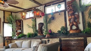 Une pièce comprenant un canapé, des meubles en osier, des œuvres d’art décoratives accrochées au mur et des lanternes suspendues.