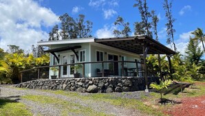 Une maison moderne avec des fondations en pierre, une véranda et une vue sur le paysage tropical environnant.