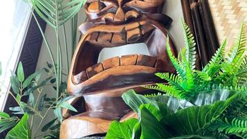 Een houten tiki-beeldje omgeven door weelderige groene planten.