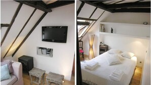A cozy attic bedroom with a bed, a TV, and a small table.