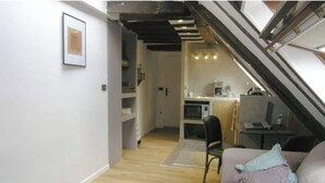A compact living space with a kitchenette, a dining area, and a staircase.