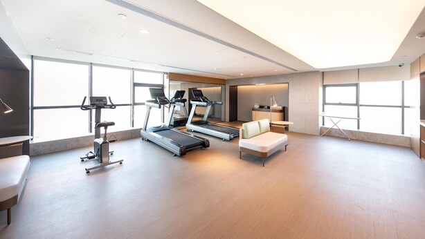 A modern fitness room with treadmills, a bench, and a desk. - Ji Hotel (Binzhou)