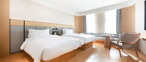 A hotel room with two beds, a desk, and a chair.