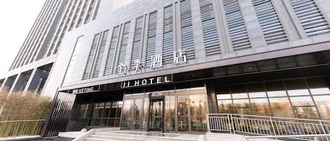 A modern hotel entrance with a prominent sign, a staircase leading up to the entrance, and a view of the surrounding high-rise buildings.