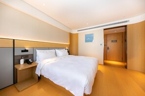 A hotel room with a bed, bedside table, and a door.