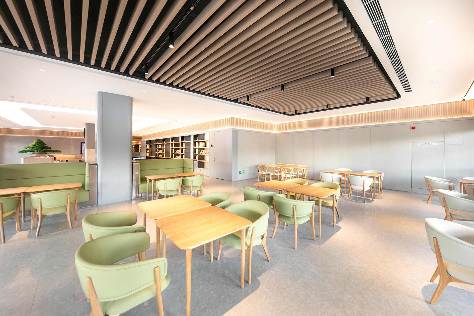 A modern library with green seating, wooden tables, and bookshelves.