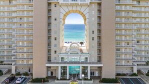 A high-rise hotel with a central atrium leading to a beach view.