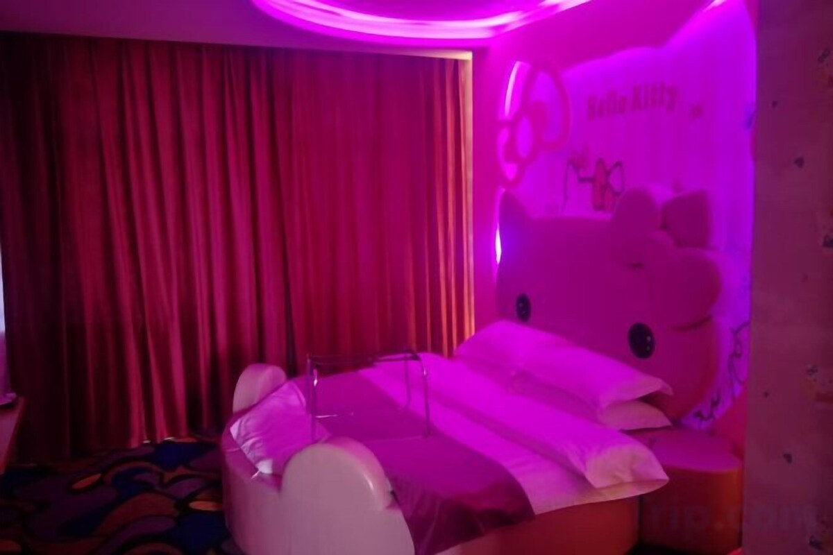 A room with a bed, a curtain, and a wall decoration.