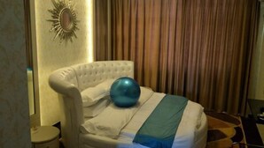 A hotel room with a tufted headboard, a large blue exercise ball, and a striped blanket. - Fenglinxuan Hotel (Ulaan Chab)