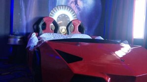 A red sports car-shaped bed with a speedometer headboard, a pillow, and a blanket. - Fenglinxuan Hotel (Ulaan Chab)