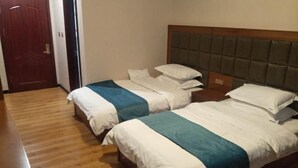 A hotel room with two beds, wooden flooring, a door, and a headboard with a padded design. - Fenglinxuan Hotel (Ulaan Chab)