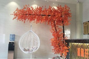 Una habitación con una hamaca colgante, dispensador de agua y una rama decorativa roja.