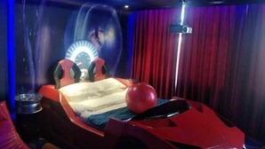 A room with a bed, a red sports car, a projector, and a red curtain. - Fenglinxuan Hotel (Ulaan Chab)