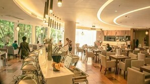 A modern restaurant with a long counter, multiple seating areas, and large windows. - Thinking Land Lingyan Forest Hotel (Dujiangyan)