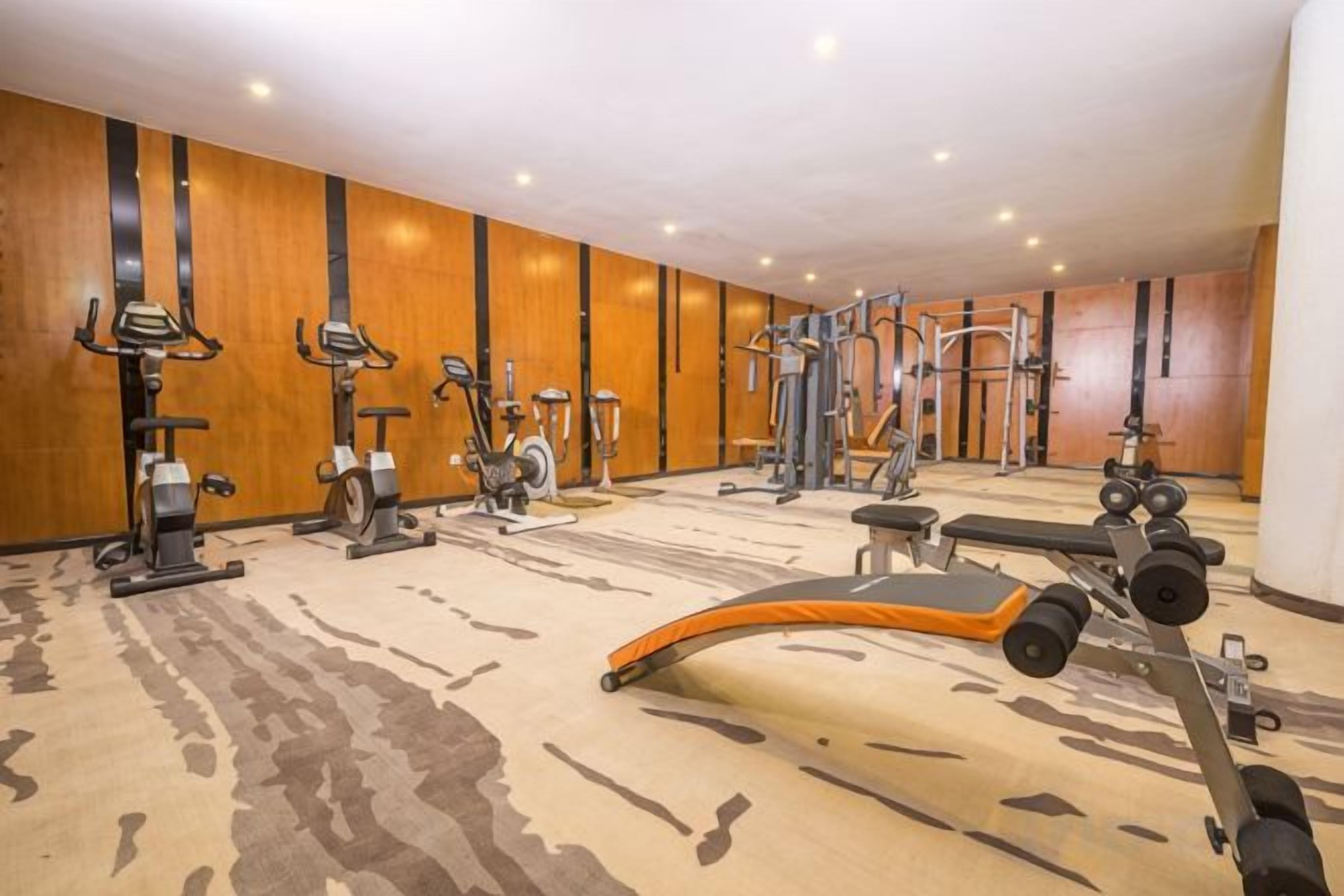 A gym with various exercise equipment including treadmills, stationary bikes, and weight machines.