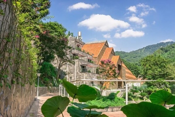 A stone building with a red-tiled roof, surrounded by greenery and a clear sky. - Thinking Land Lingyan Forest Hotel (Dujiangyan)