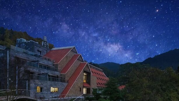 A modern building with a red roof, surrounded by lush greenery and a starry night sky. - Thinking Land Lingyan Forest Hotel (Dujiangyan)