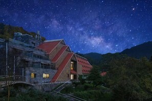 A modern building with a red roof, surrounded by lush greenery and a starry night sky. - Thinking Land Lingyan Forest Hotel (Dujiangyan)