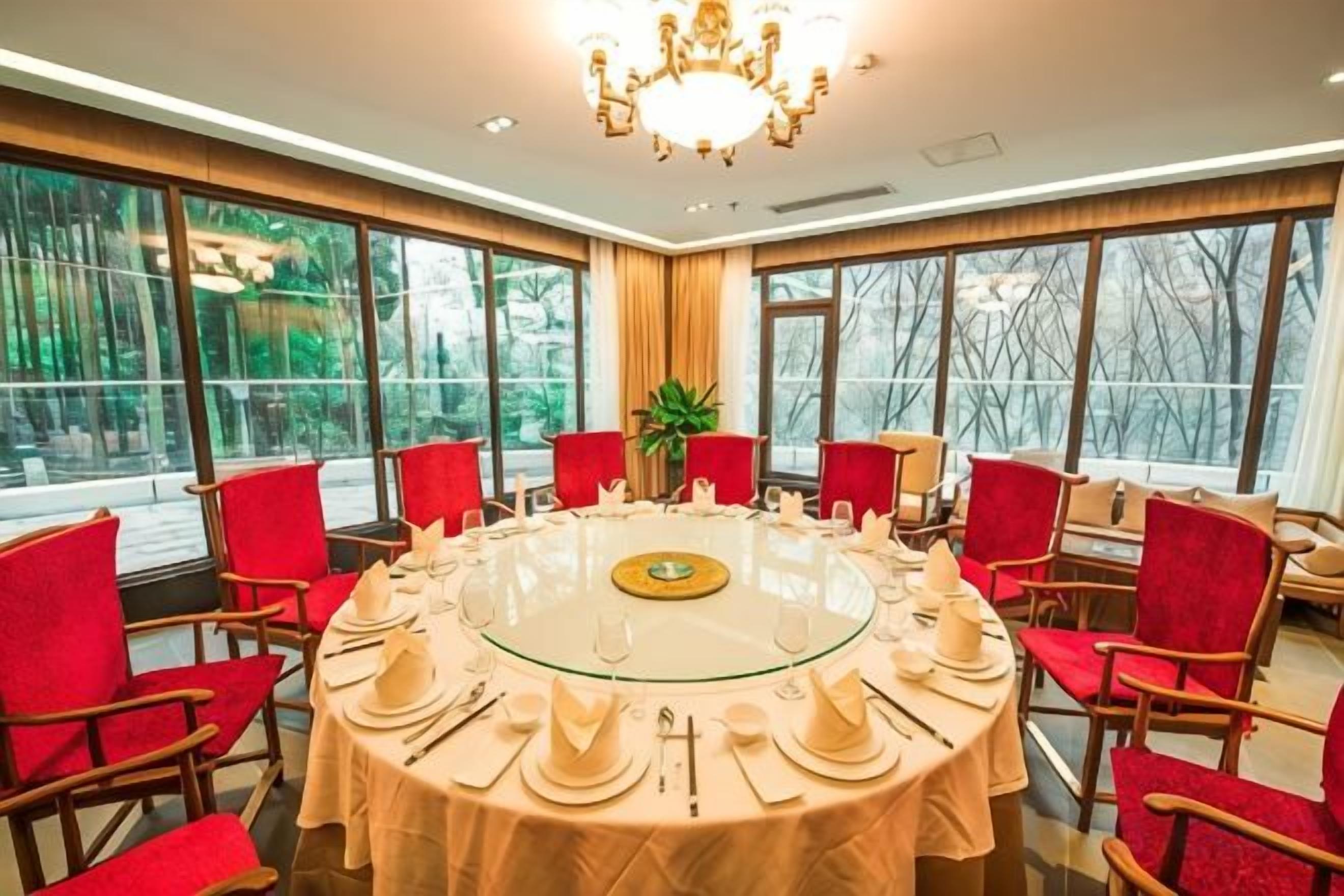 Un salón de conferencias con una mesa redonda, sillas rojas y una araña de cristal.
