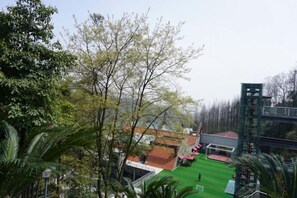 A residential area with a green lawn, a red-roofed building, and a tall structure in the background. - Thinking Land Lingyan Forest Hotel (Dujiangyan)