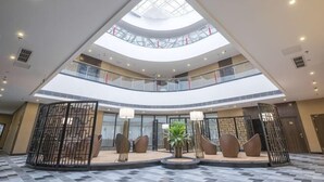 A multi-level atrium with a skylight, a central seating area, and a patterned floor. - Thinking Land Lingyan Forest Hotel (Dujiangyan)