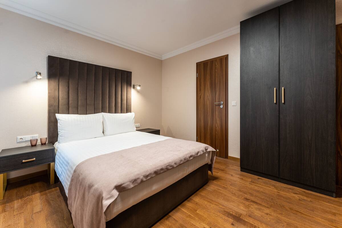 A bedroom with a bed, bedside tables, a wardrobe, and a headboard.