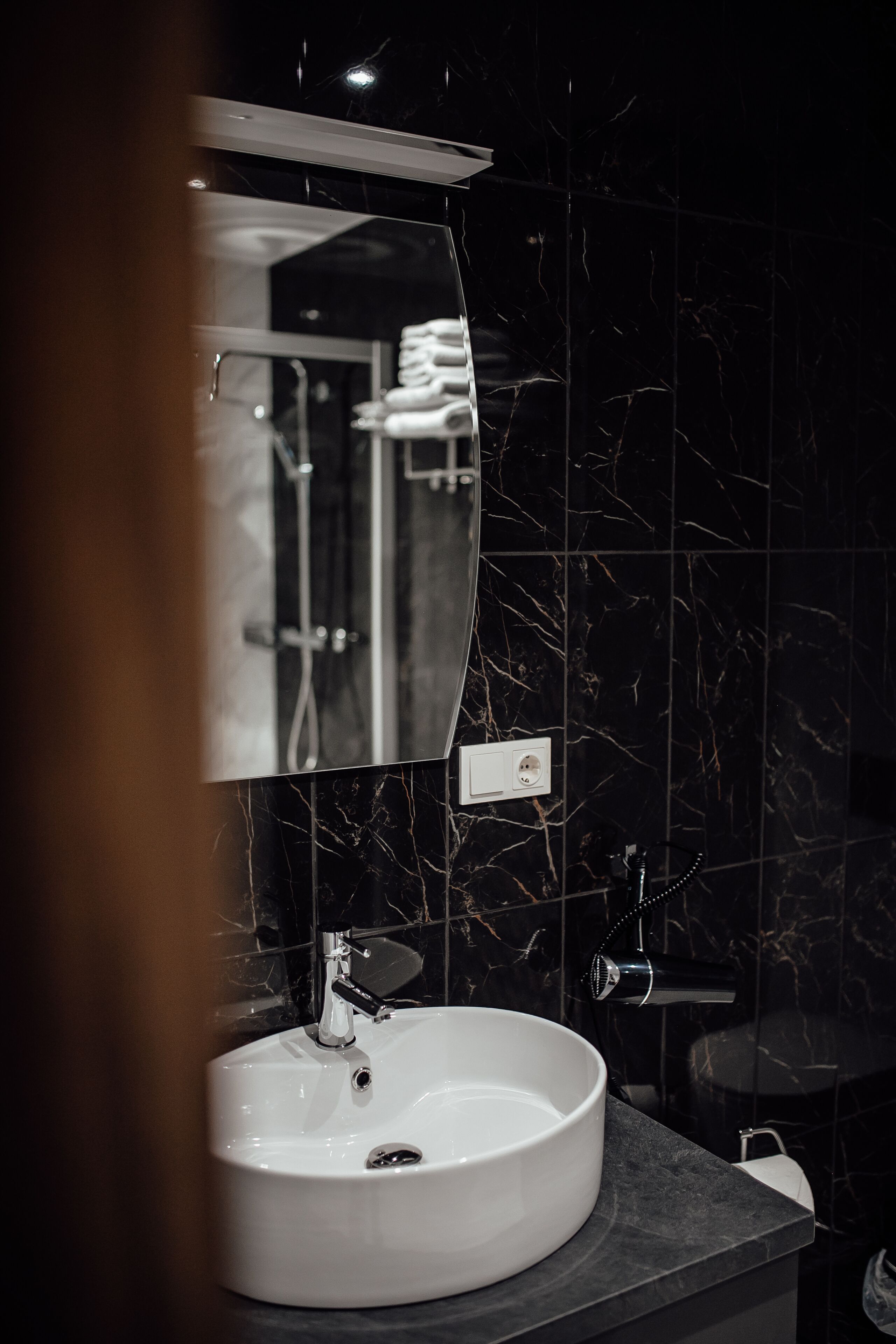 A bathroom with a white sink, a mirror, and a shower area.
