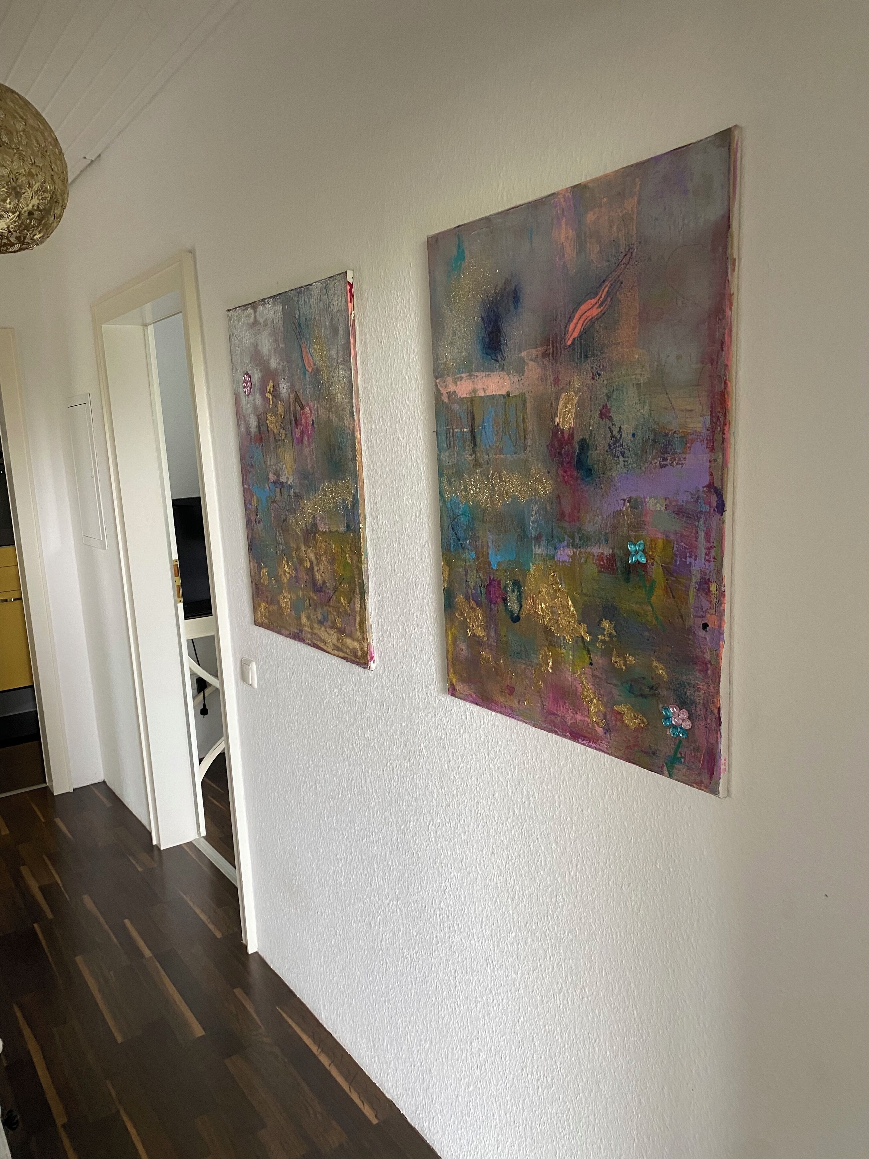 Un pasillo con dos cuadros abstractos en la pared y una puerta que da a otra habitación.