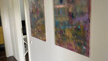 Un pasillo con dos cuadros abstractos en la pared y una puerta que da a otra habitación.
