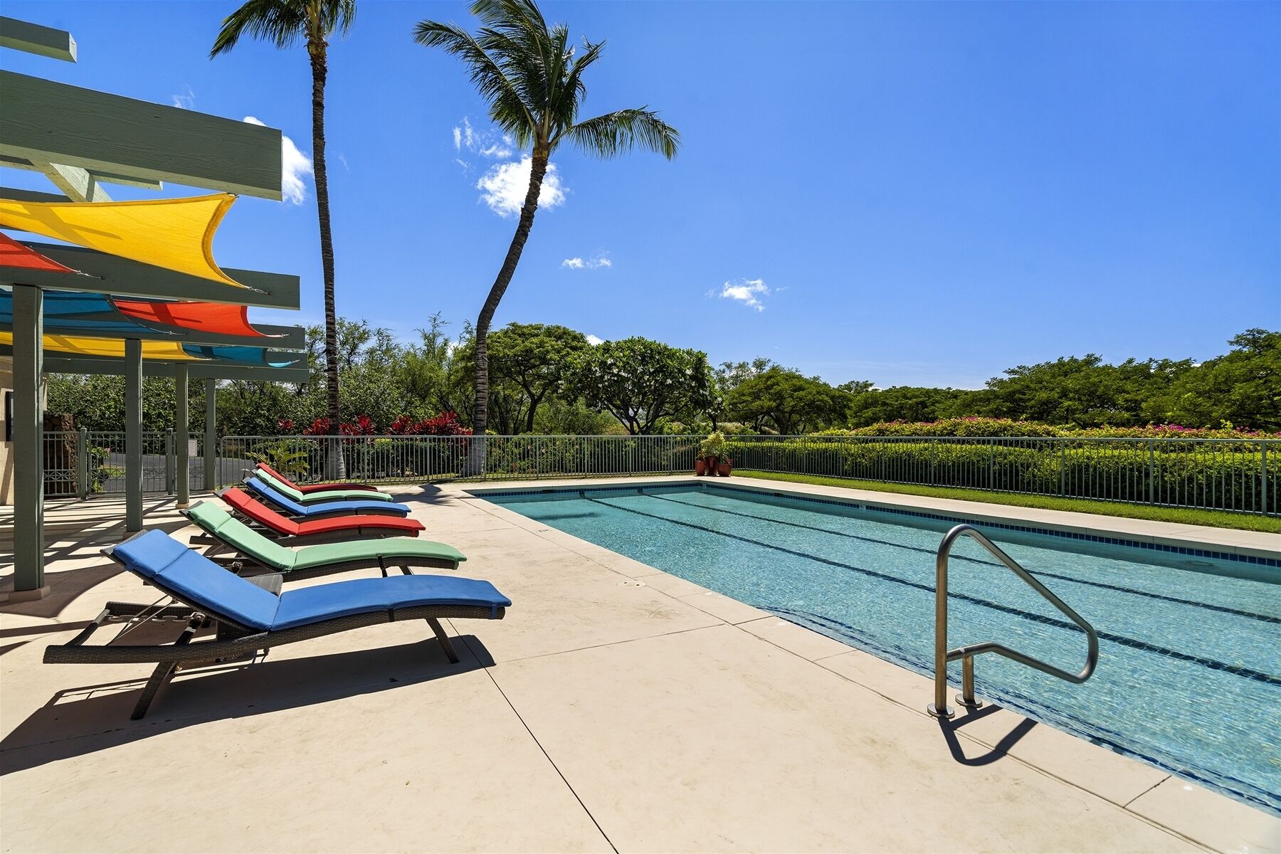A swimming pool with lounge chairs and a covered area with colorful umbrellas.