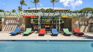 A poolside area with lounge chairs and a pergola providing shade.