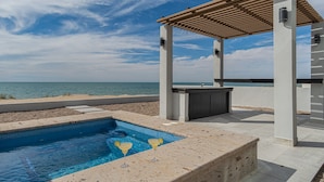 Zona de piscina con una pérgola, un bar y vistas al mar.